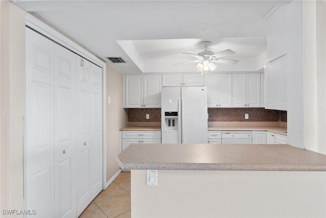 kitchen with white appliances, light tile patterned floors, decorative backsplash, and white cabinets