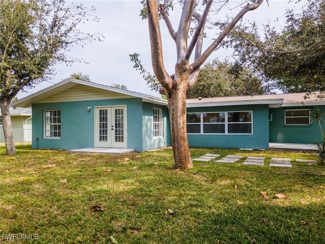 back of property featuring french doors and a lawn