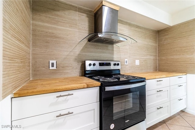 kitchen with white cabinetry, wooden counters, light tile patterned floors, electric stove, and wall chimney range hood