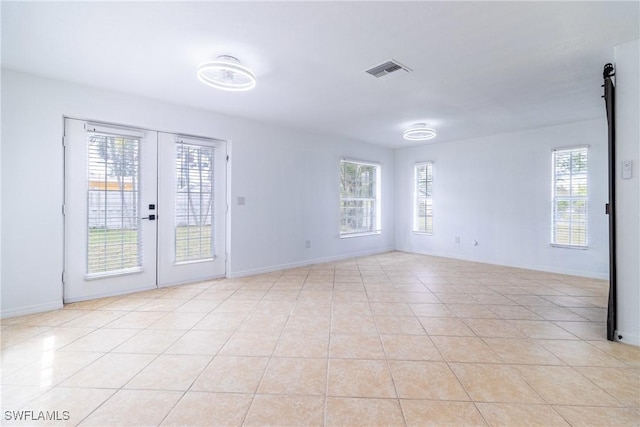 tiled empty room featuring french doors and a wealth of natural light