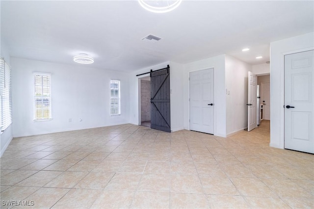 empty room featuring light tile patterned flooring and a barn door