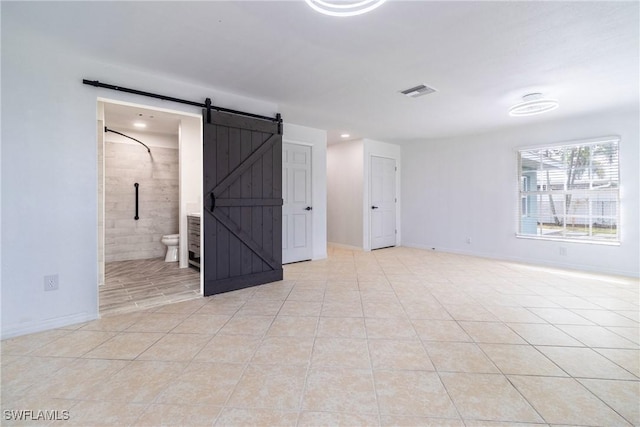 tiled spare room featuring a barn door