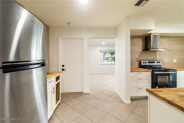 kitchen with decorative backsplash, stainless steel appliances, white cabinets, wall chimney exhaust hood, and wood counters