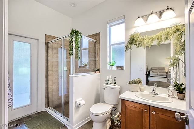 bathroom with wood-type flooring, toilet, a shower with shower door, and vanity