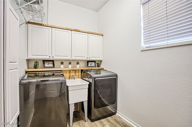 laundry room with cabinets, light hardwood / wood-style flooring, and independent washer and dryer