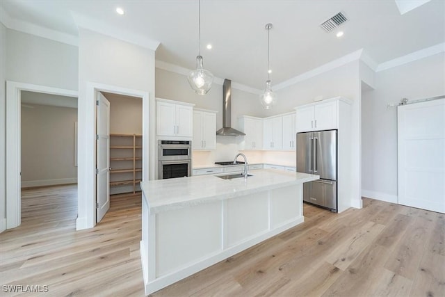 kitchen with pendant lighting, white cabinets, wall chimney exhaust hood, and stainless steel appliances