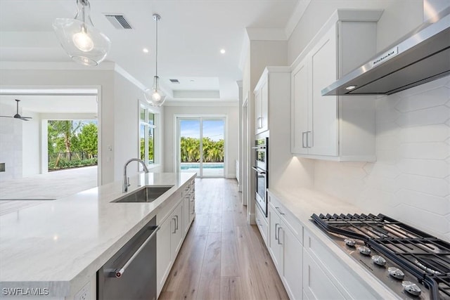 kitchen with white cabinets, appliances with stainless steel finishes, wall chimney exhaust hood, and pendant lighting