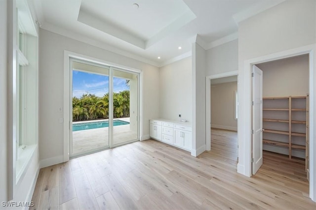 unfurnished room featuring light hardwood / wood-style floors, a tray ceiling, and crown molding