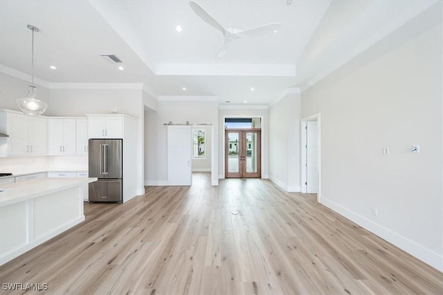 interior space featuring french doors, light wood-type flooring, ceiling fan, crown molding, and a barn door