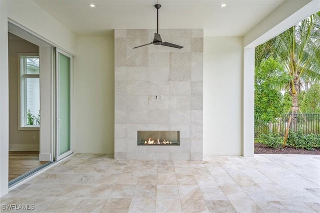 view of patio with ceiling fan and a fireplace