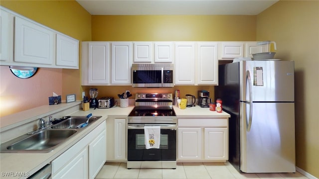 kitchen with stainless steel appliances, light tile patterned flooring, sink, and white cabinets