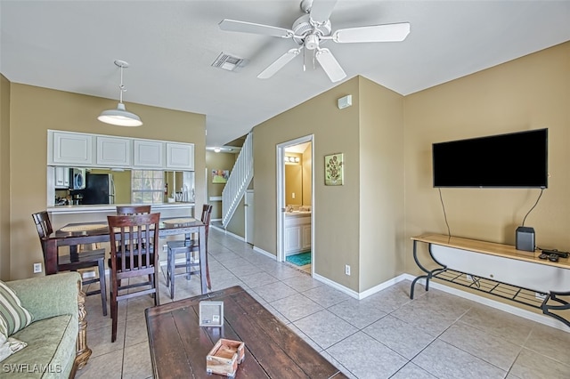 living area featuring light tile patterned floors, baseboards, visible vents, and a ceiling fan