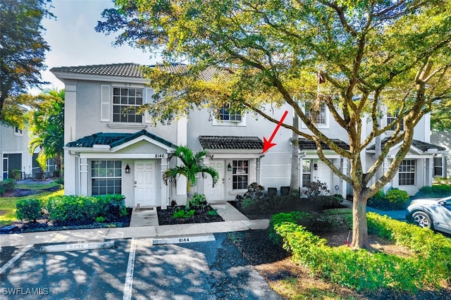 view of front of home featuring uncovered parking, a tiled roof, and stucco siding