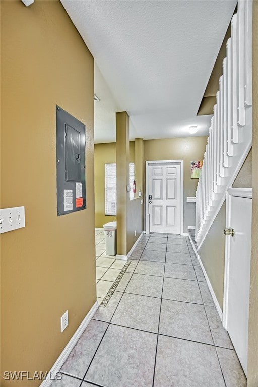 corridor with light tile patterned floors, stairway, electric panel, and baseboards