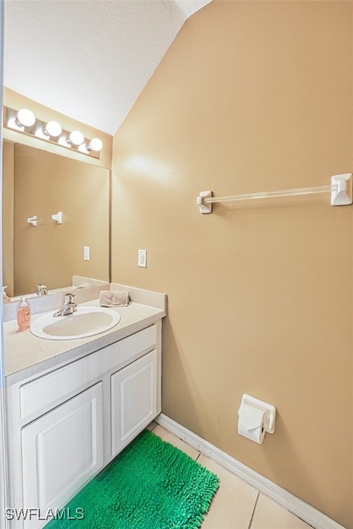 bathroom featuring vaulted ceiling, tile patterned flooring, vanity, and baseboards