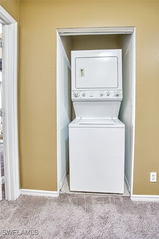 washroom with light carpet, stacked washer and dryer, laundry area, and baseboards