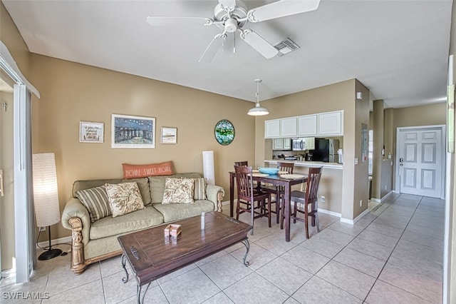 living area featuring light tile patterned floors, baseboards, visible vents, and a ceiling fan