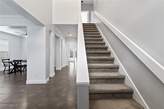 stairway with crown molding and ceiling fan