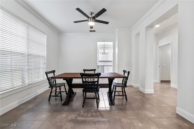 dining area with crown molding, ceiling fan with notable chandelier, and dark tile patterned floors