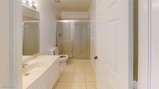 bathroom with tile patterned floors, toilet, a shower with door, and vanity