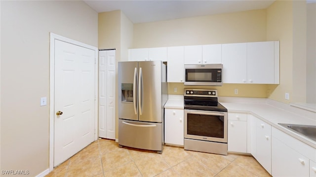 kitchen featuring white cabinetry, sink, light tile patterned floors, and stainless steel appliances