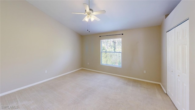 unfurnished bedroom with ceiling fan, light colored carpet, and a closet