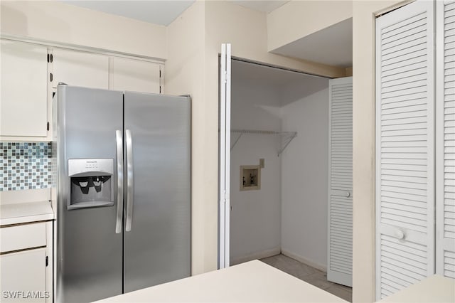 kitchen featuring backsplash, white cabinets, and stainless steel fridge