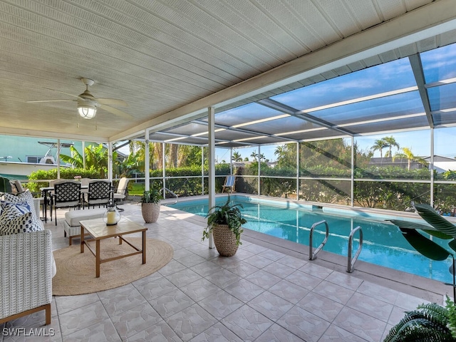 view of pool featuring glass enclosure, a patio, and ceiling fan