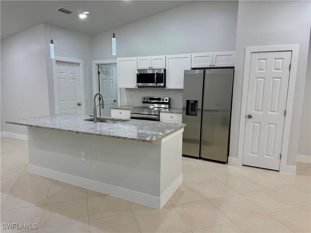 kitchen with white cabinetry, sink, stainless steel appliances, light stone counters, and a center island with sink