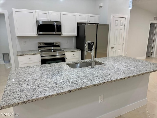 kitchen with sink, a large island with sink, light stone countertops, and appliances with stainless steel finishes