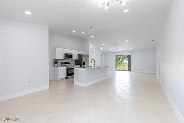 kitchen featuring appliances with stainless steel finishes, decorative light fixtures, lofted ceiling, white cabinets, and a center island with sink