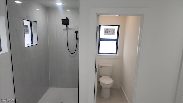 bathroom with toilet, a tile shower, and tile patterned flooring