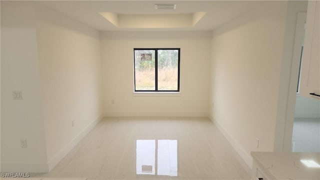 unfurnished room with a tray ceiling and light tile patterned floors