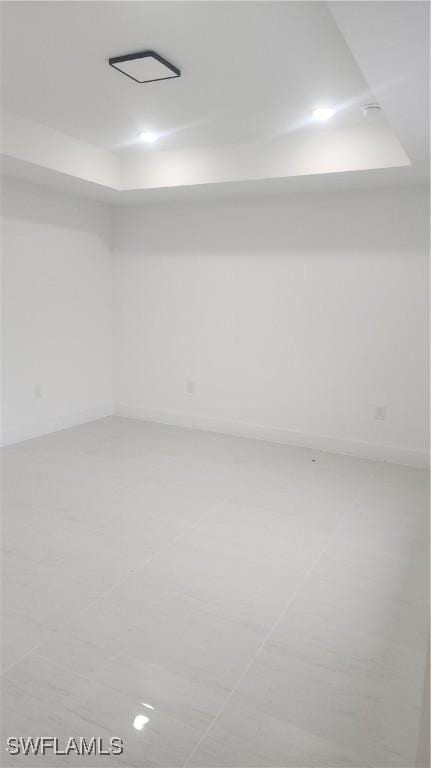 tiled empty room featuring a tray ceiling