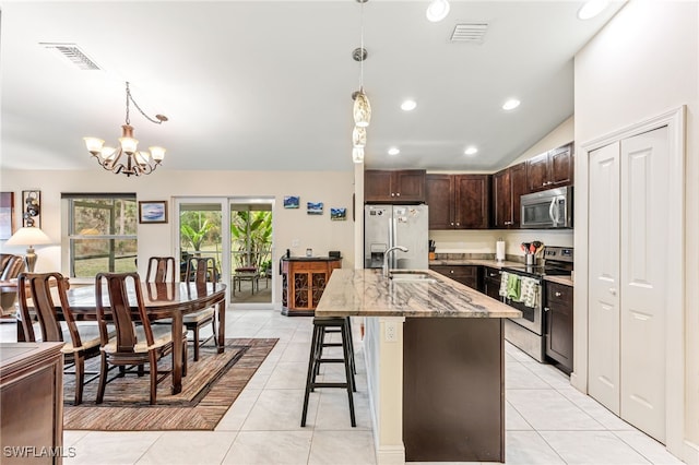 kitchen with light tile patterned flooring, stainless steel appliances, a breakfast bar, and decorative light fixtures