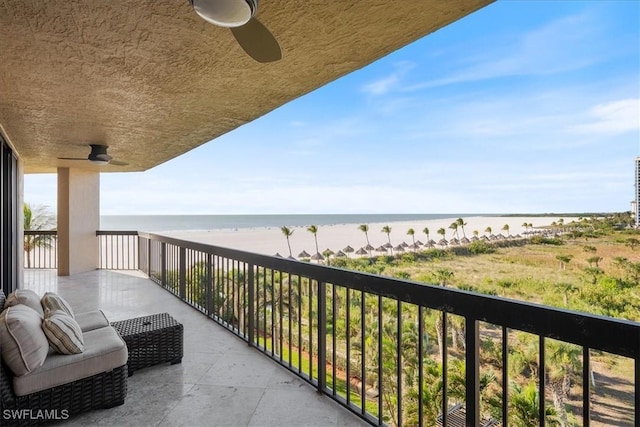 balcony with ceiling fan, a water view, and a beach view