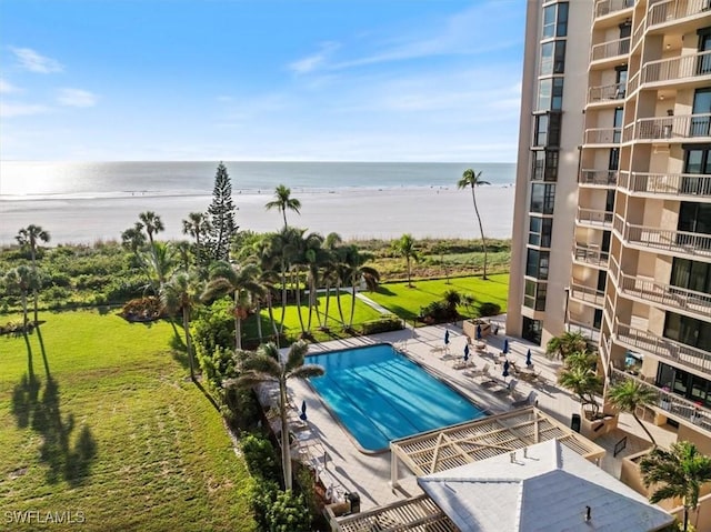 view of pool with a water view, a lawn, a patio area, and a beach view