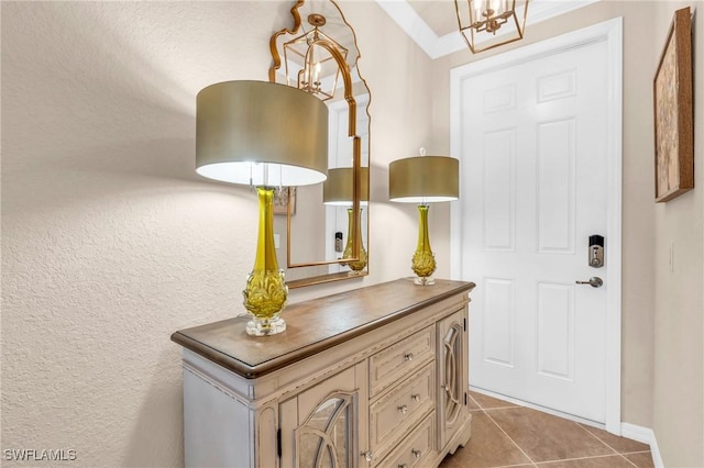 tiled foyer featuring an inviting chandelier and ornamental molding