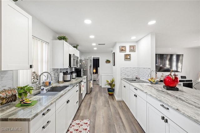 kitchen with white cabinets, sink, light stone counters, and stainless steel appliances