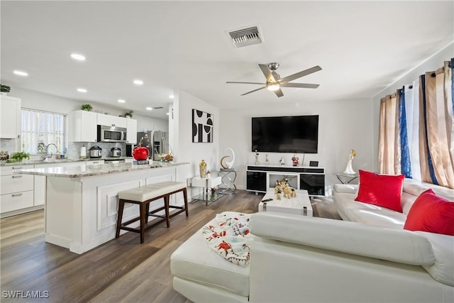 living room with ceiling fan, dark wood-type flooring, and sink