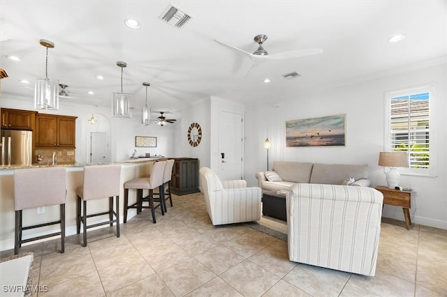 tiled living room featuring ornamental molding and ceiling fan