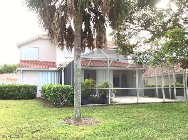 back of property featuring a lanai, a lawn, and a patio area