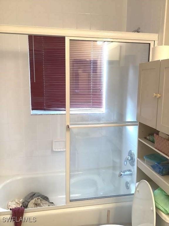 bathroom with bath / shower combo with glass door and toilet