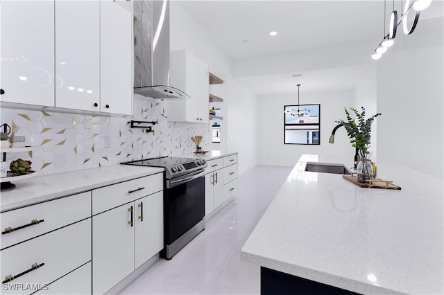 kitchen featuring pendant lighting, white cabinets, wall chimney exhaust hood, stainless steel range with electric cooktop, and sink