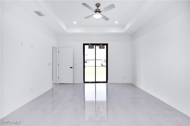 spare room featuring ceiling fan and a tray ceiling