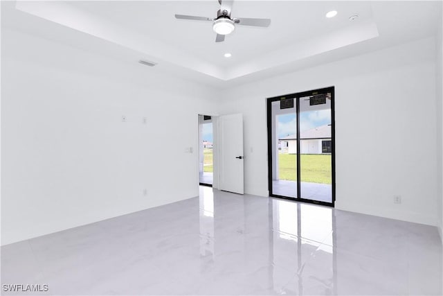 unfurnished room featuring ceiling fan and a raised ceiling