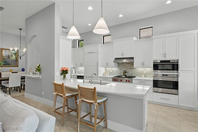 kitchen with tasteful backsplash, sink, hanging light fixtures, and white cabinets