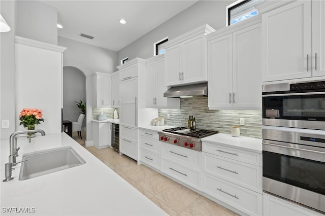 kitchen with sink, white cabinetry, tasteful backsplash, appliances with stainless steel finishes, and beverage cooler