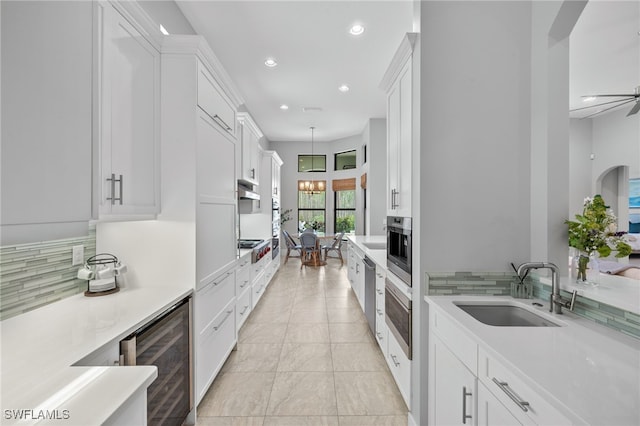 kitchen featuring white cabinetry, sink, tasteful backsplash, and wine cooler