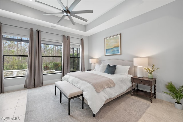 tiled bedroom with a raised ceiling and ceiling fan